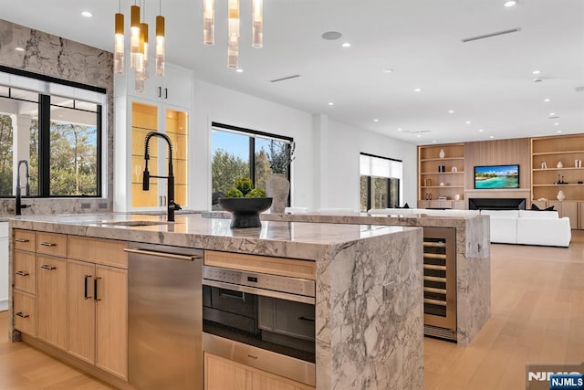 kitchen with a spacious island, light brown cabinets, a sink, and light wood finished floors