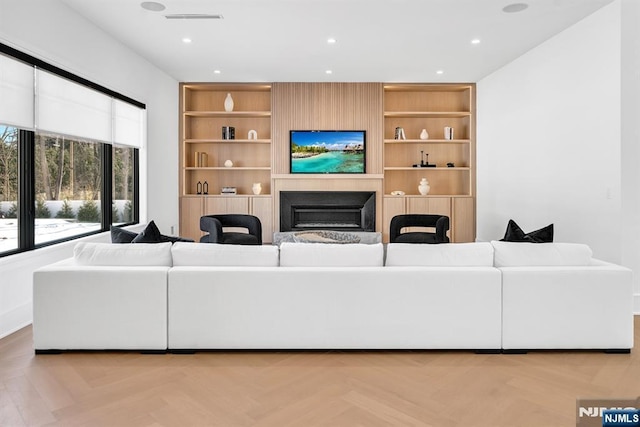 living area featuring built in shelves, recessed lighting, visible vents, and a fireplace