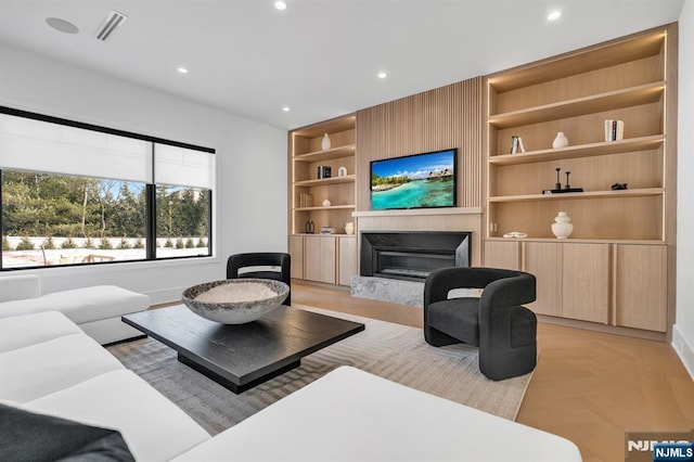 living area with built in shelves, a fireplace, visible vents, and recessed lighting