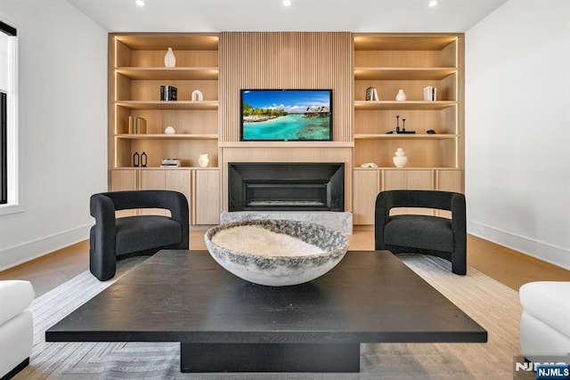 living area with a large fireplace, baseboards, built in features, and recessed lighting