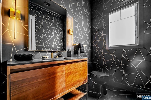 bathroom featuring toilet, vanity, and tile walls