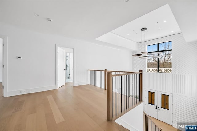 hallway with light wood finished floors, baseboards, an upstairs landing, and recessed lighting