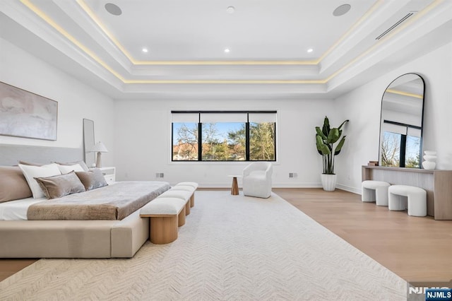 bedroom featuring visible vents, multiple windows, a tray ceiling, and wood finished floors