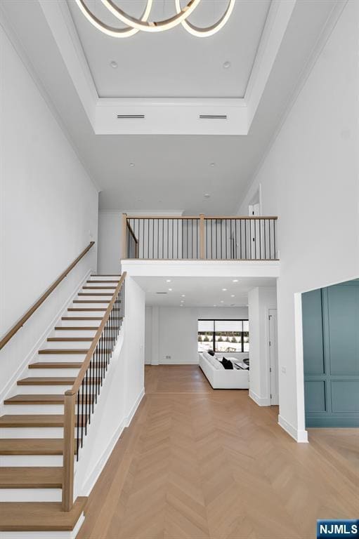 stairs featuring visible vents, a high ceiling, and baseboards