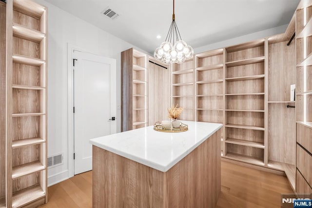 spacious closet with a chandelier, visible vents, and light wood-style flooring