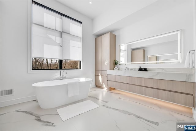 bathroom with a freestanding bath, marble finish floor, visible vents, and vanity