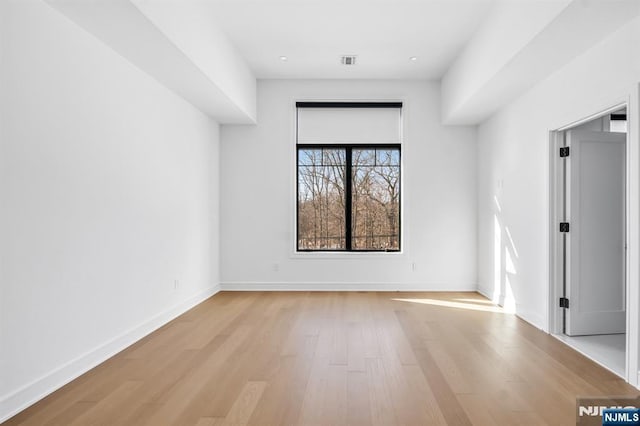 spare room with light wood-style floors, visible vents, and baseboards