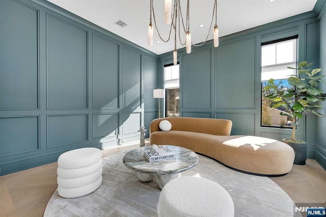 sitting room with an inviting chandelier, visible vents, and a decorative wall