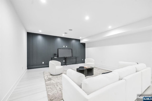 living room with baseboards, an accent wall, visible vents, and recessed lighting