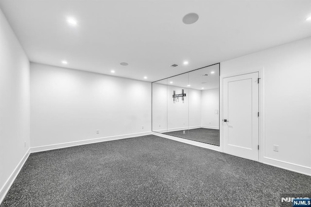 basement with baseboards, dark colored carpet, and recessed lighting