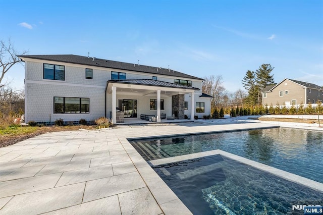 rear view of property with a patio, an in ground hot tub, and an outdoor pool