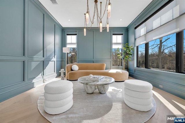 living area featuring ornamental molding, a decorative wall, and a notable chandelier