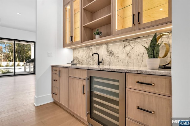 bar with wine cooler, baseboards, light wood-type flooring, backsplash, and indoor wet bar