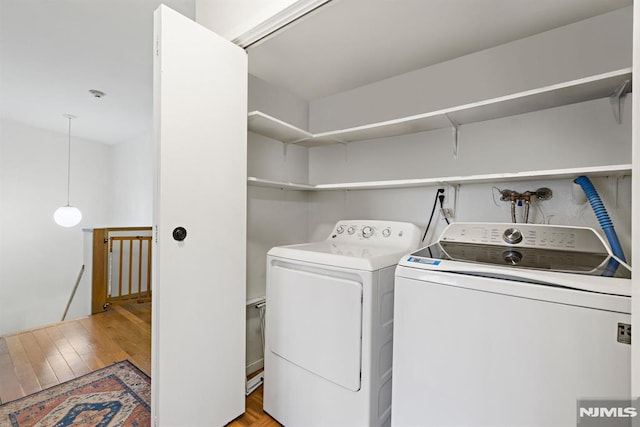 washroom with separate washer and dryer, laundry area, and light wood finished floors