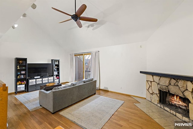 living room with a fireplace, baseboards, a ceiling fan, and wood-type flooring