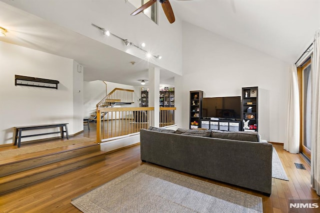 living room with stairway, a ceiling fan, visible vents, and wood-type flooring