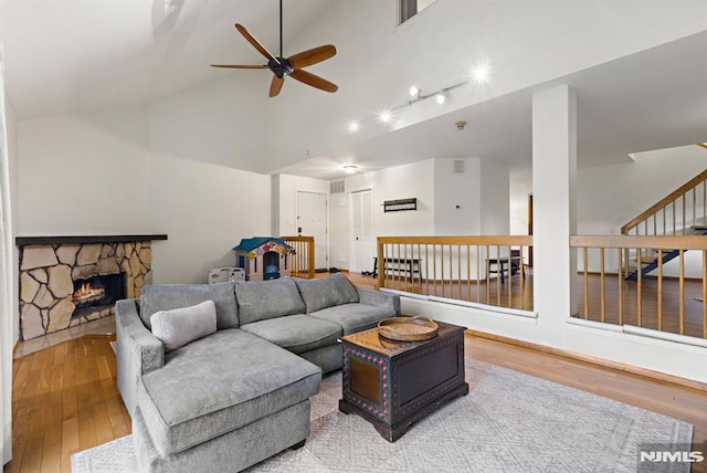 living room with stairway, a fireplace, high vaulted ceiling, a ceiling fan, and wood-type flooring