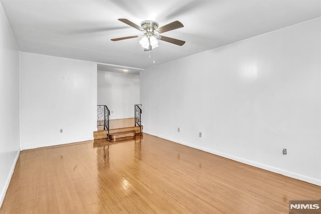 unfurnished room with ceiling fan, wood finished floors, and baseboards