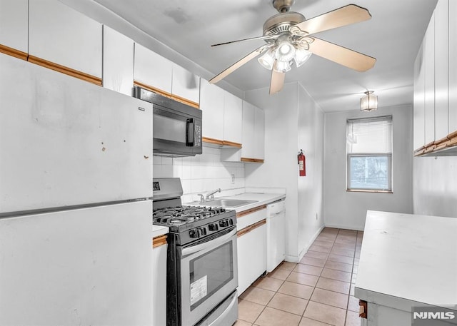 kitchen featuring light tile patterned floors, tasteful backsplash, light countertops, a sink, and white appliances