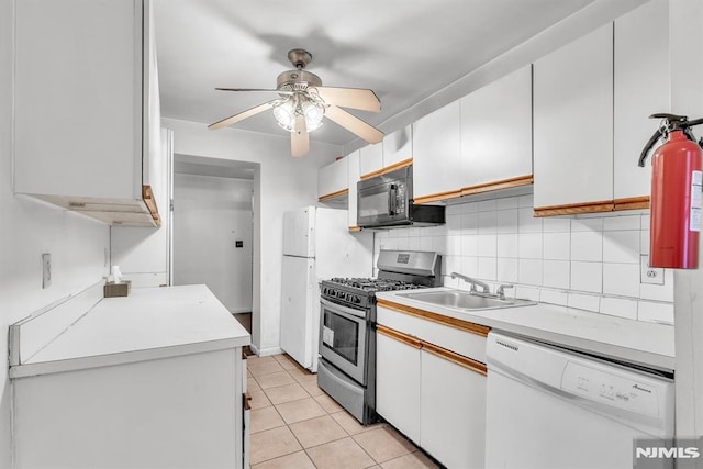 kitchen featuring light tile patterned floors, white appliances, a sink, light countertops, and decorative backsplash