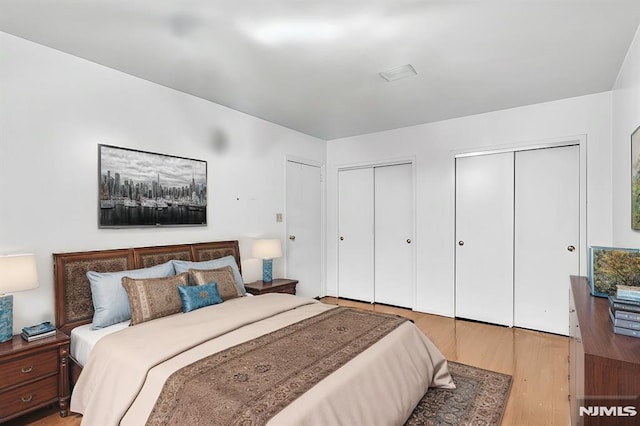 bedroom with light wood-style flooring and multiple closets