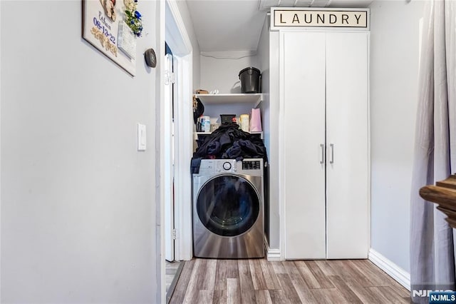 clothes washing area with washer / dryer, wood finished floors, and laundry area