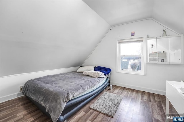 bedroom with baseboards, lofted ceiling, and wood finished floors