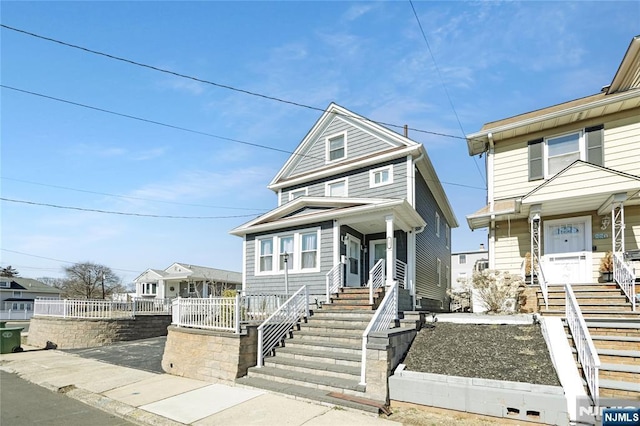 american foursquare style home with stairway, covered porch, and fence