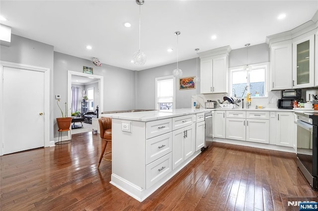 kitchen featuring a breakfast bar area, a peninsula, dark wood-type flooring, white cabinetry, and range