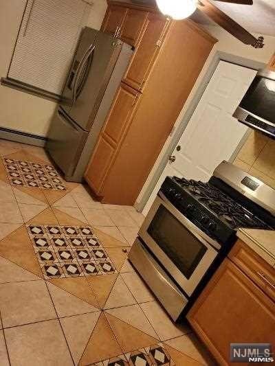 kitchen featuring a baseboard radiator, light tile patterned flooring, and gas range