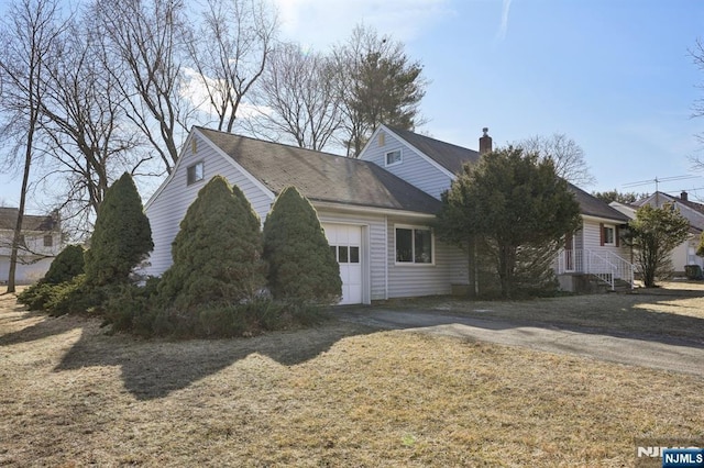 view of side of property featuring a garage, driveway, and a chimney