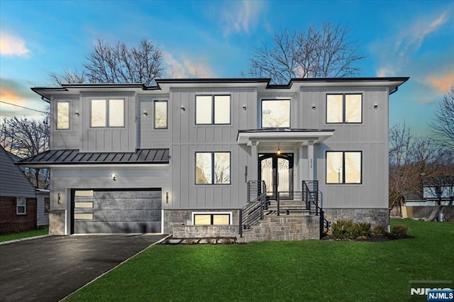 modern farmhouse featuring driveway, a garage, a standing seam roof, a yard, and board and batten siding