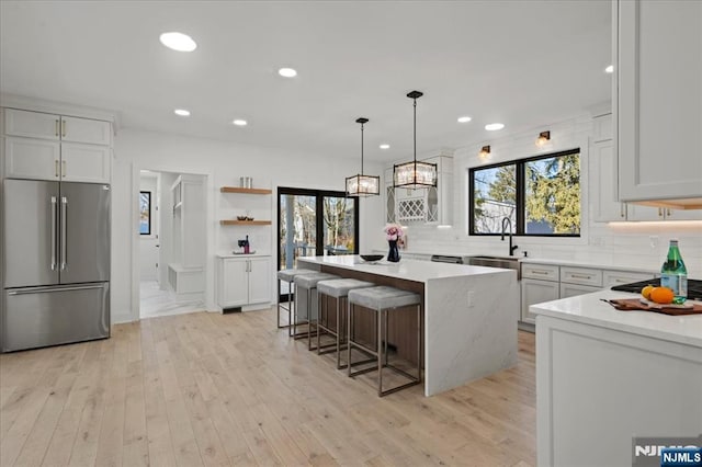 kitchen featuring a sink, light wood-style floors, appliances with stainless steel finishes, decorative backsplash, and a center island