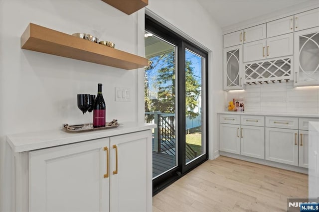 bar featuring light wood-type flooring, a dry bar, and backsplash