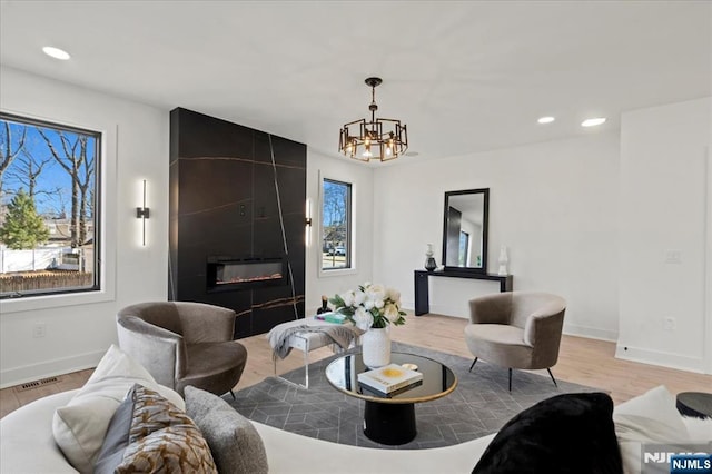 living area featuring recessed lighting, light wood-type flooring, a fireplace, and baseboards