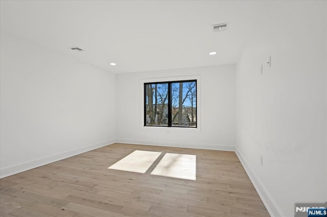 empty room with recessed lighting, wood finished floors, visible vents, and baseboards