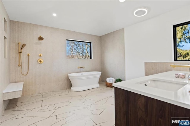 full bathroom with marble finish floor, tiled shower, a freestanding bath, and vanity