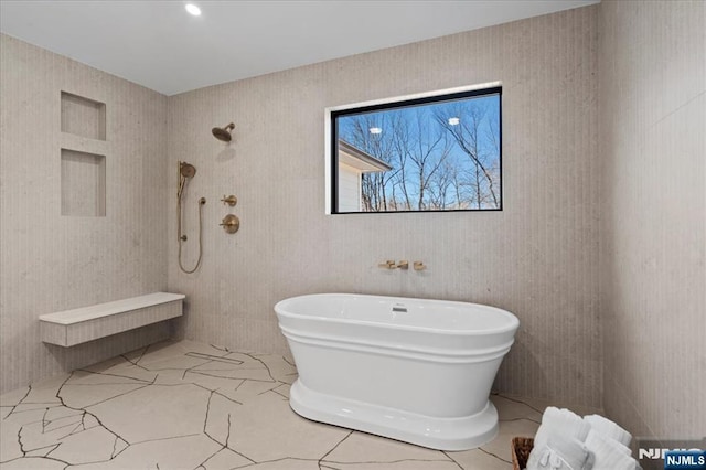 bathroom featuring marble finish floor, tiled shower, and a freestanding tub