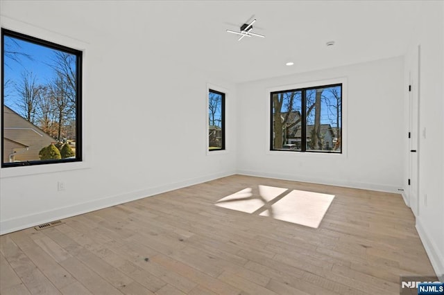 empty room with baseboards, light wood-style flooring, and a healthy amount of sunlight