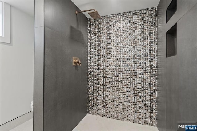 full bathroom with tiled shower and toilet