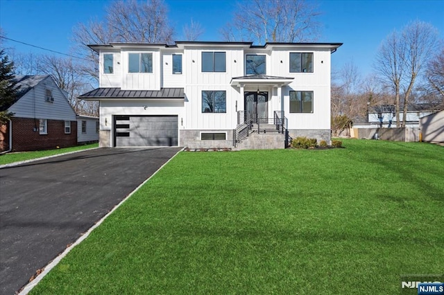 view of front facade with board and batten siding, a front yard, a standing seam roof, a garage, and driveway