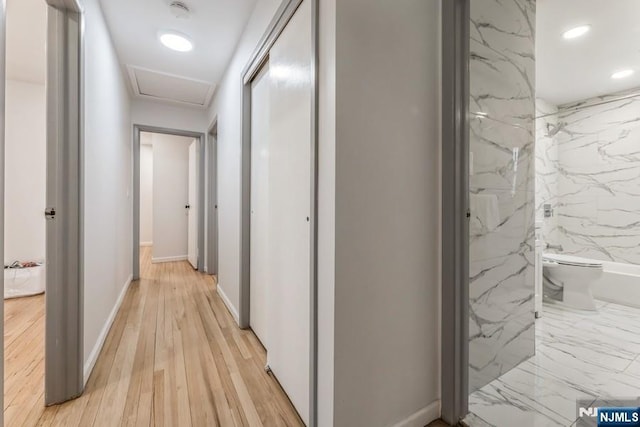 hallway with light wood-type flooring, attic access, baseboards, and recessed lighting