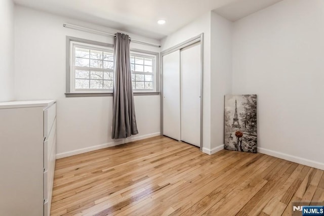 unfurnished bedroom with recessed lighting, a closet, light wood-style flooring, and baseboards