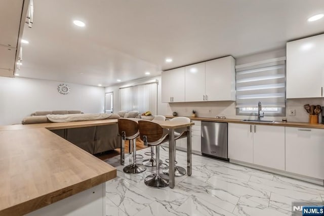 kitchen featuring butcher block countertops, open floor plan, a sink, and stainless steel dishwasher