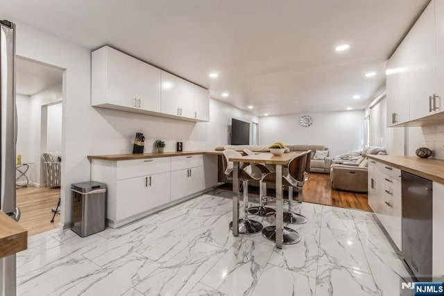 kitchen featuring recessed lighting, butcher block counters, white cabinets, and open floor plan