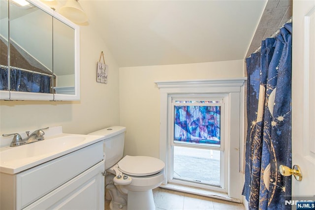 bathroom with toilet, tile patterned floors, vaulted ceiling, and vanity