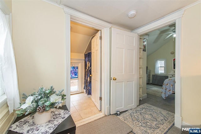 hallway with tile patterned flooring, vaulted ceiling, and carpet flooring