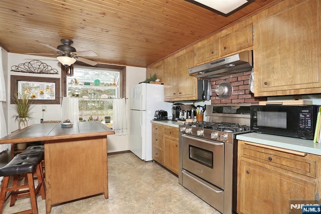 kitchen featuring black microwave, wooden ceiling, under cabinet range hood, stainless steel range with gas cooktop, and freestanding refrigerator