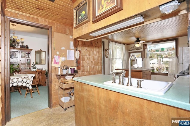 kitchen featuring light countertops, light carpet, a sink, ceiling fan, and wooden ceiling