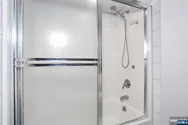 bathroom featuring combined bath / shower with glass door